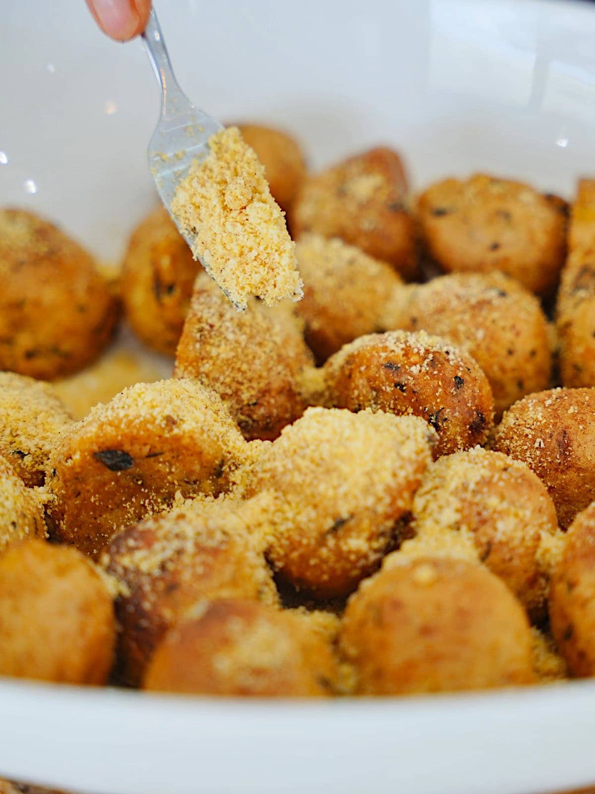 Close-up of crispy potato balls, sprinkled with vegan Parmesan