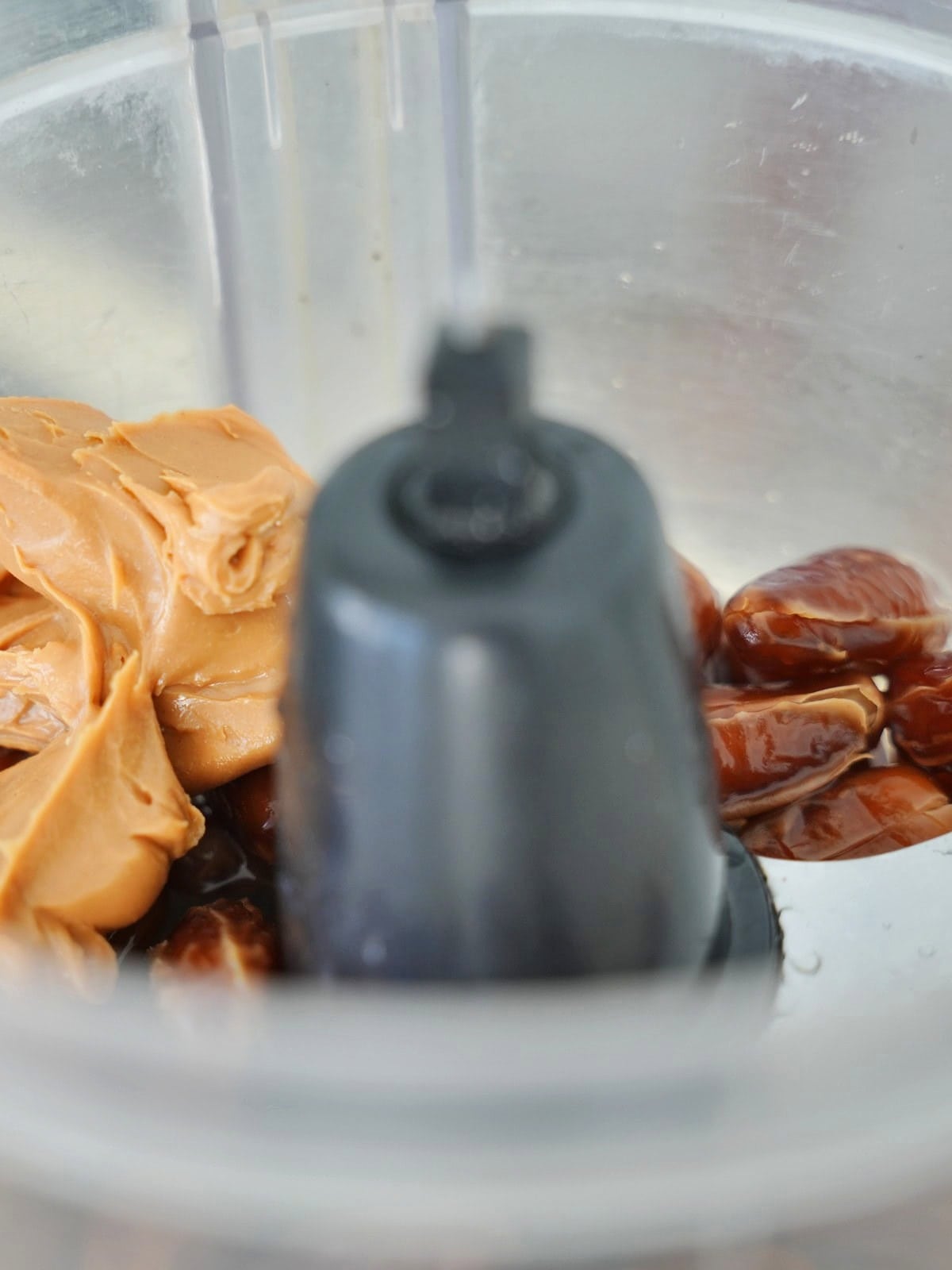 Creamy peanut butter and whole dates sit in a food processor, ready for blending