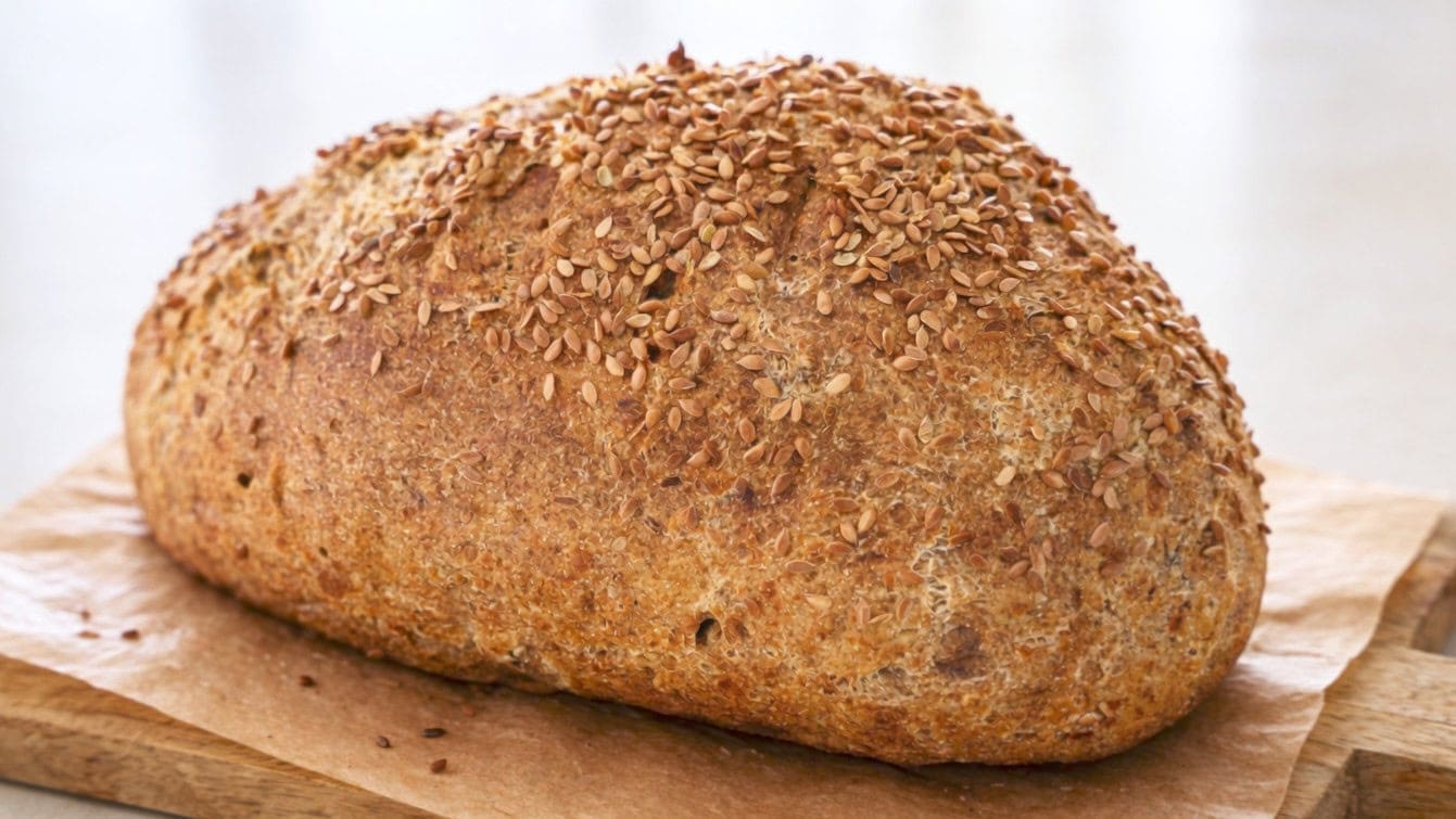 A hearty loaf of freshly baked chickpea flour bread, topped with flax seeds