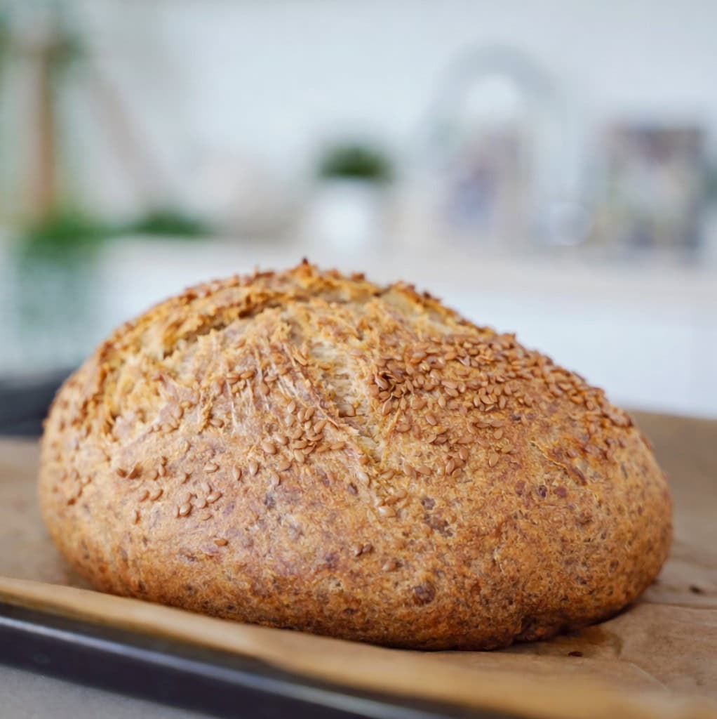 Freshly baked loaf of chickpea flour bread sprinkled with flax seeds
