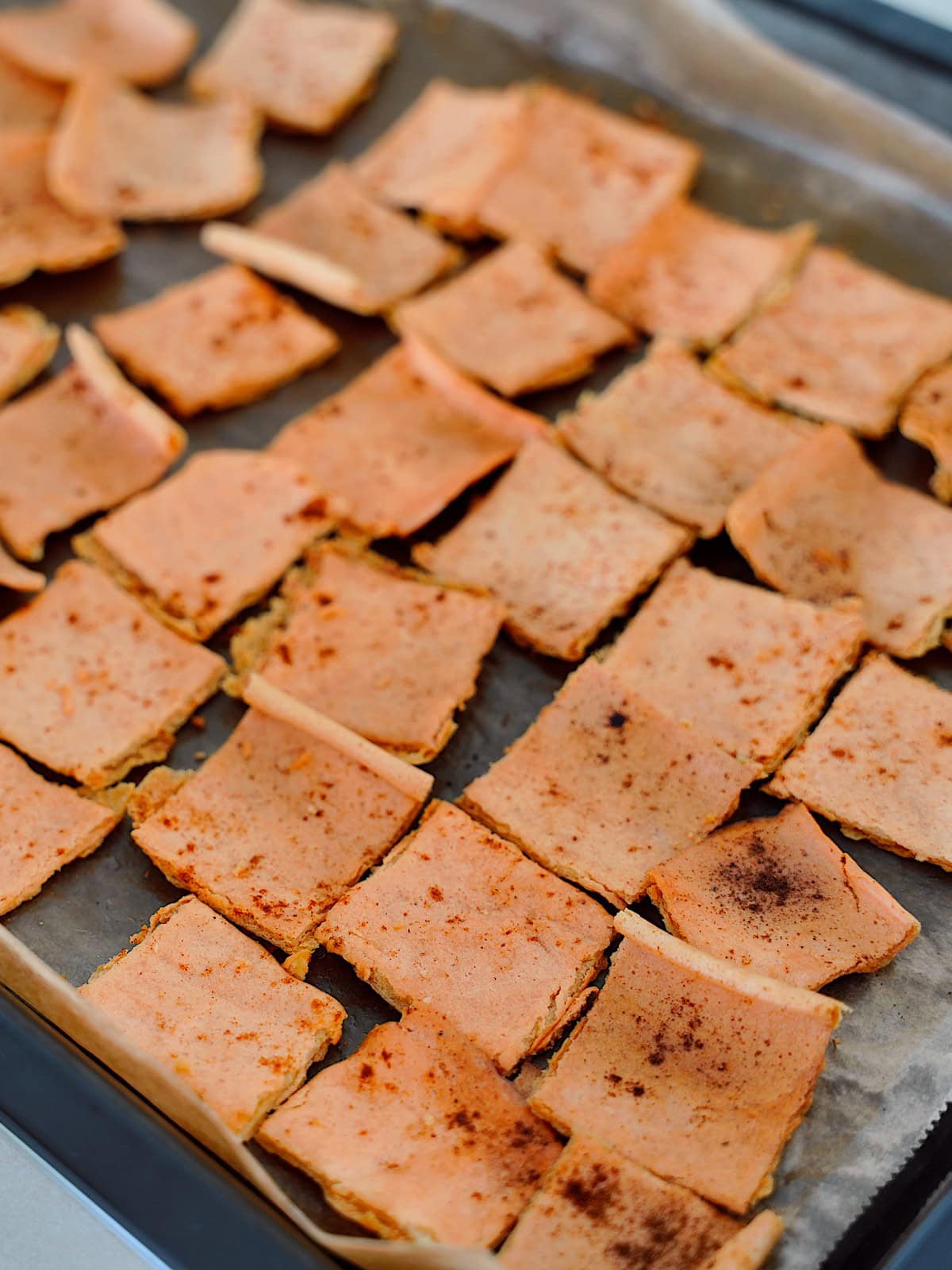 Baked lentil crackers arranged on a parchment-lined baking sheet