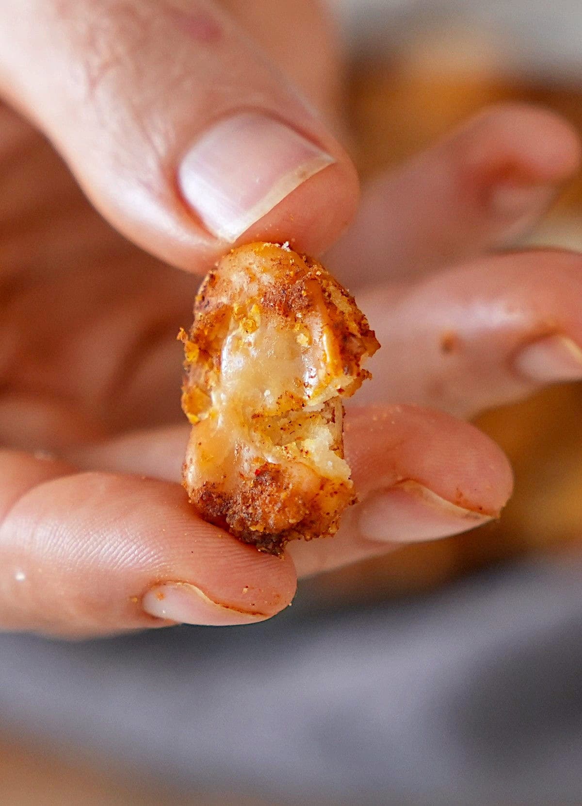Eine Hand hält ein knuspriges, goldbraunes Stück geröstete Riesenbohne