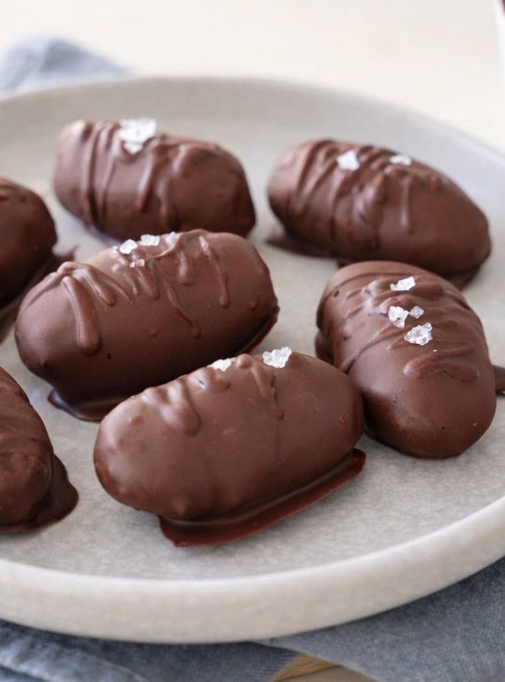 Sieben schokoladenüberzogene Pralinen auf einem grauen Teller 