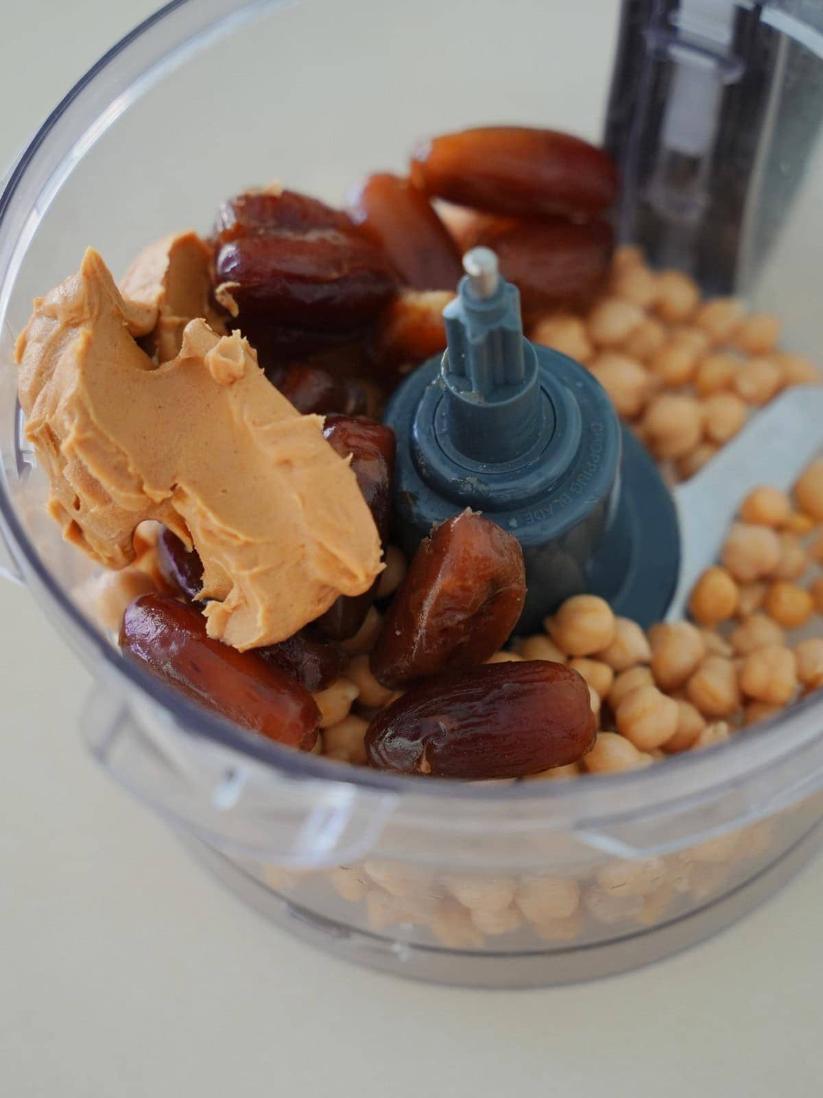 Kichererbsen, Datteln und Erdnussbutter in einer transparenten Küchenmaschinen-Schüssel 