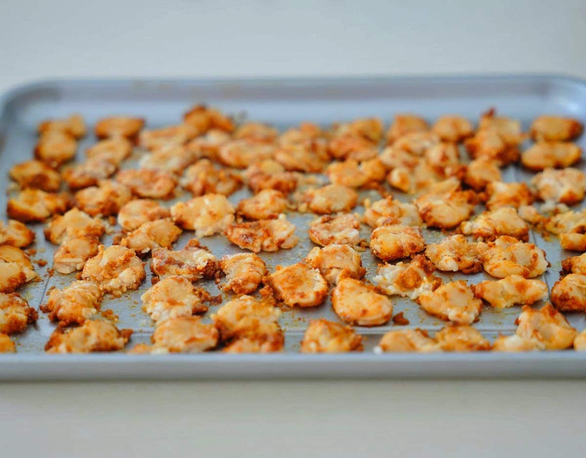 Nahaufnahme eines Backblechs, gefüllt mit goldbraunen, leicht gewürzten Limabohnen, vor dem Backen