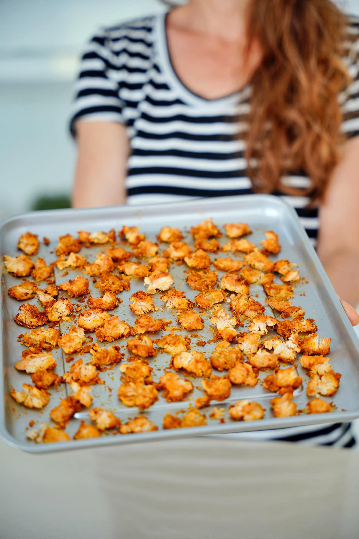 Elavegan hält ein Blech mit knusprig gerösteten Riesenbohnen aus dem Airfryer in der Hand