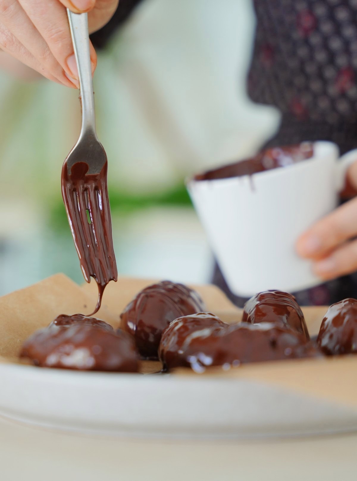 Elavegan beträufelt schokoladenüberzogene Pralinen mit einer Gabel und geschmolzener Zartbitterschokolade 