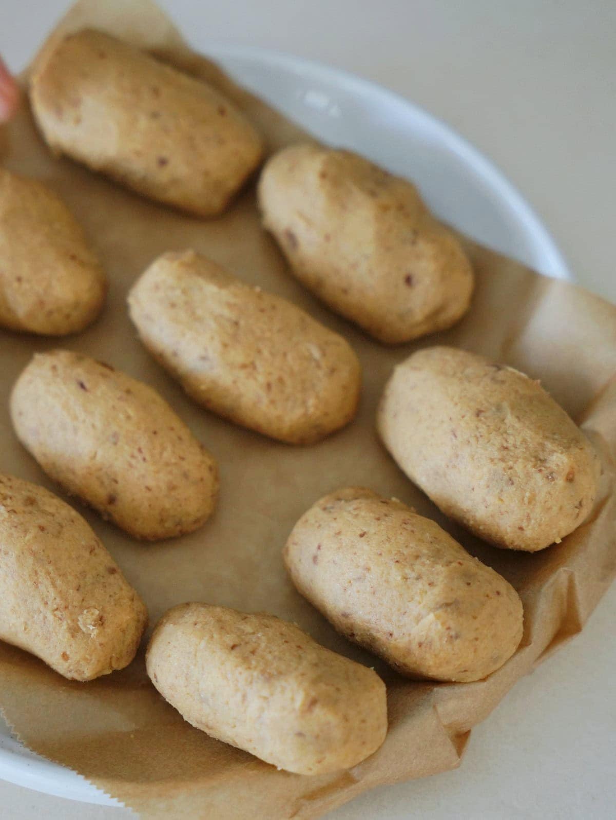 Neun kleine, längliche hellbraune Riegel auf braunem Backpapier 