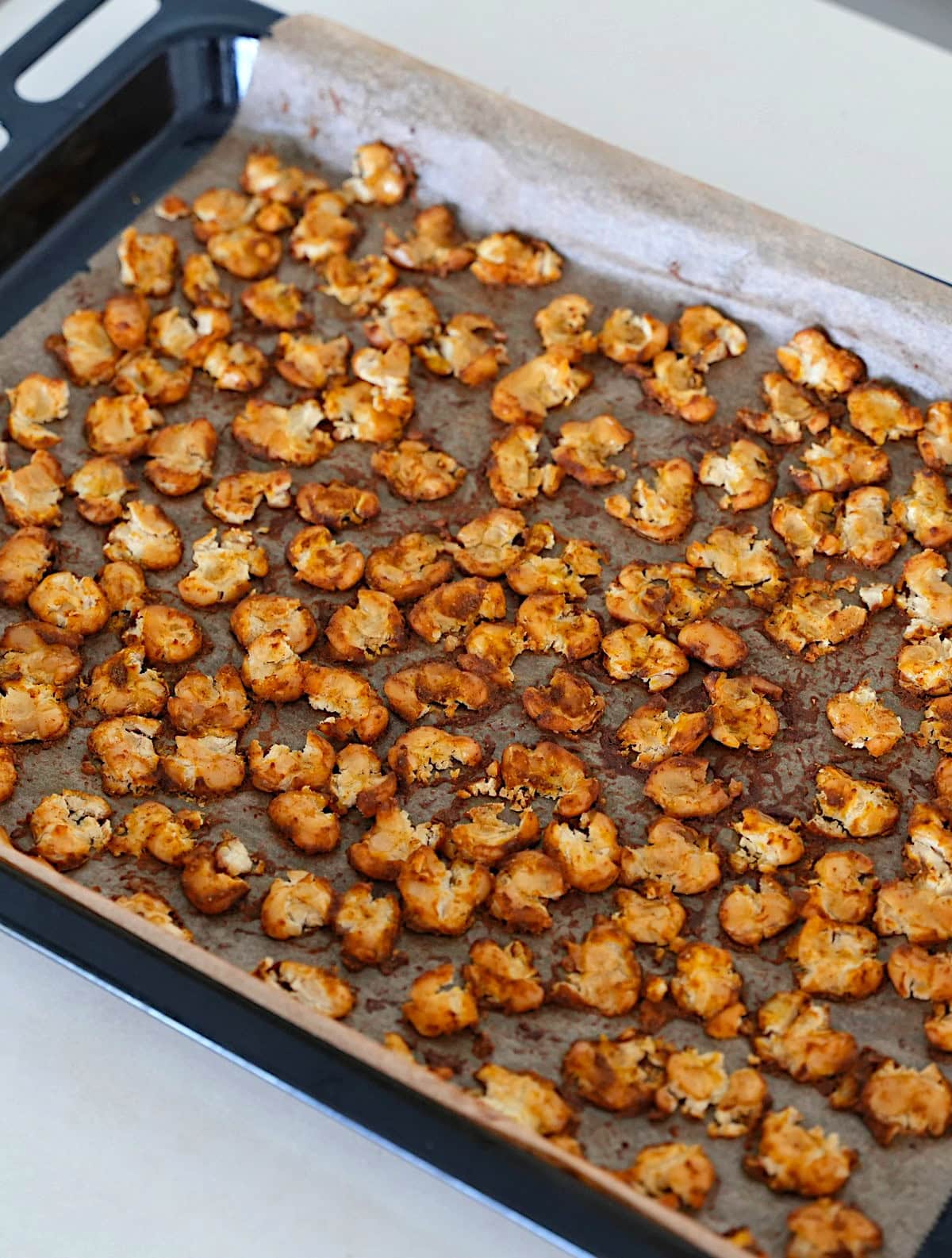 Geröstete Riesenbohnen, auf einem mit Backpapier ausgelegten Backblech verteilt, goldbraun und knusprig