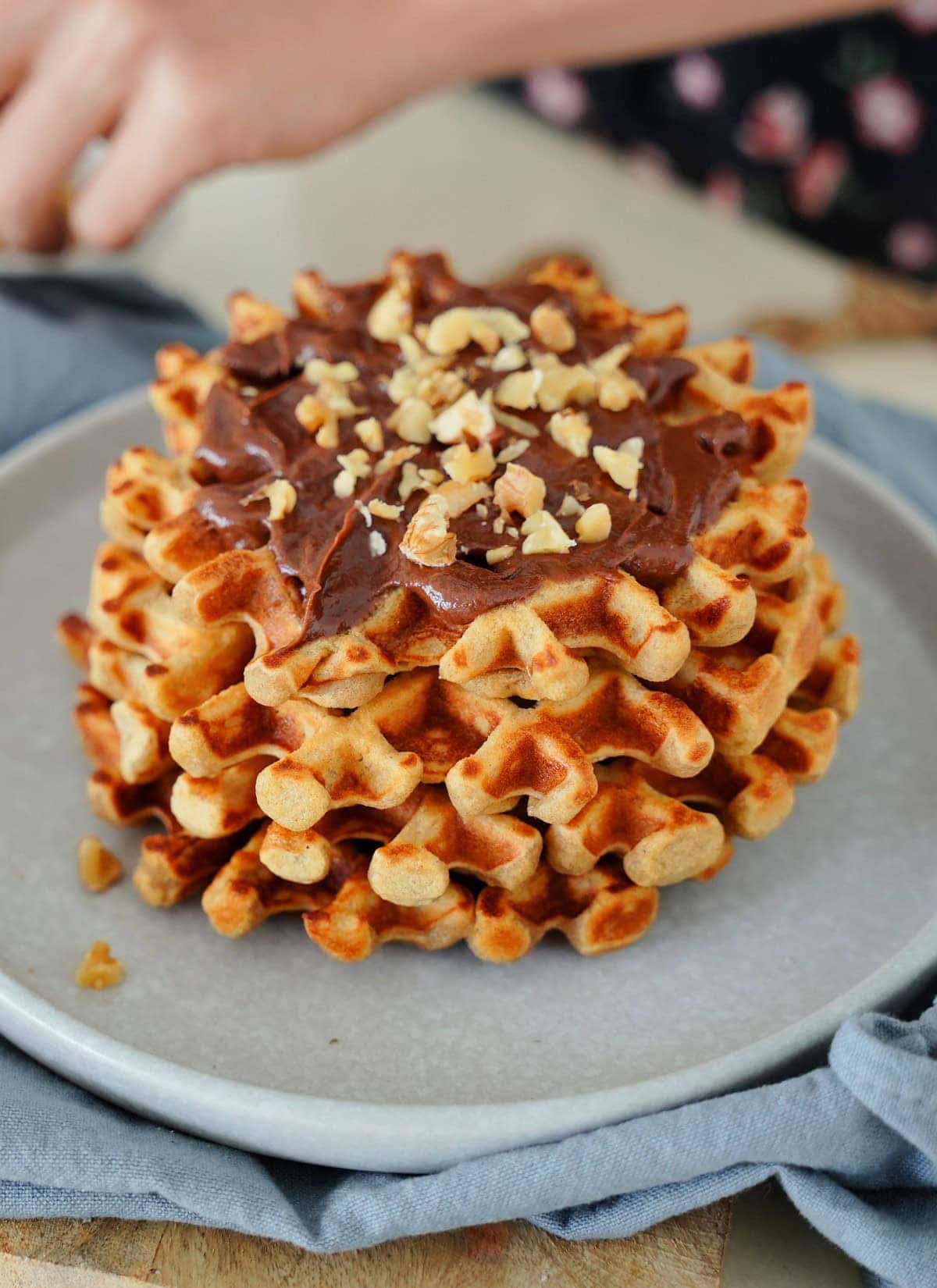 A stack of golden brown red lentil waffles topped with chocolate spread and crushed nuts