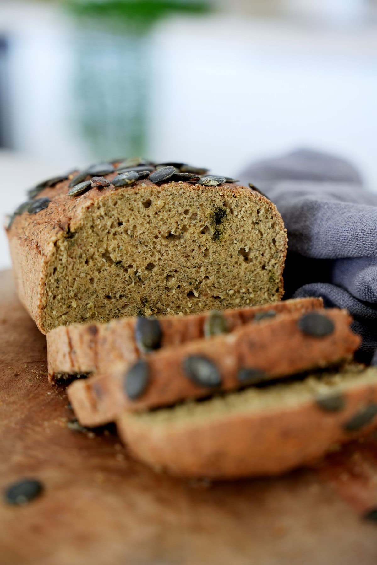 Sliced lentil loaf topped with pumpkin seeds on wooden board.