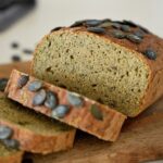 Sliced red lentil bread topped with pumpkin seeds.