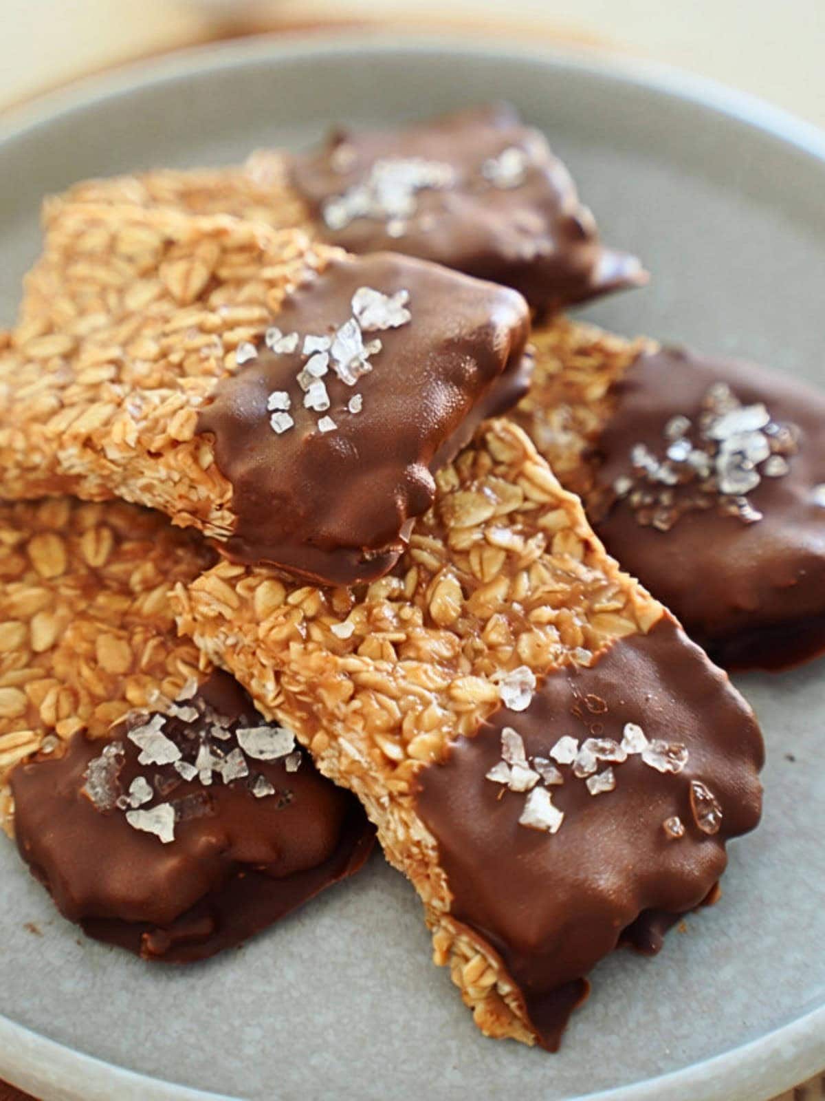 peanut butter oat bars with chocolate and coarse salt on gray plate.