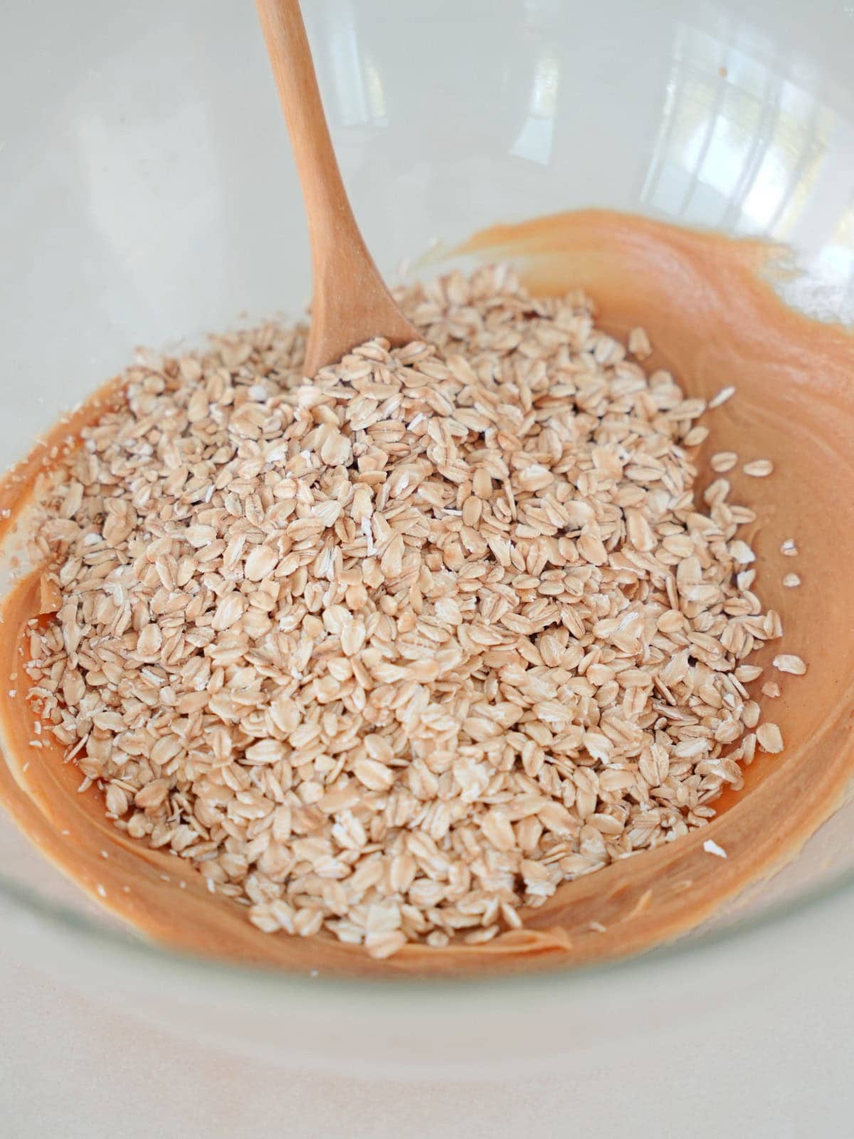 peanut butter with toasted oats and wooden spoon in glass bowl.