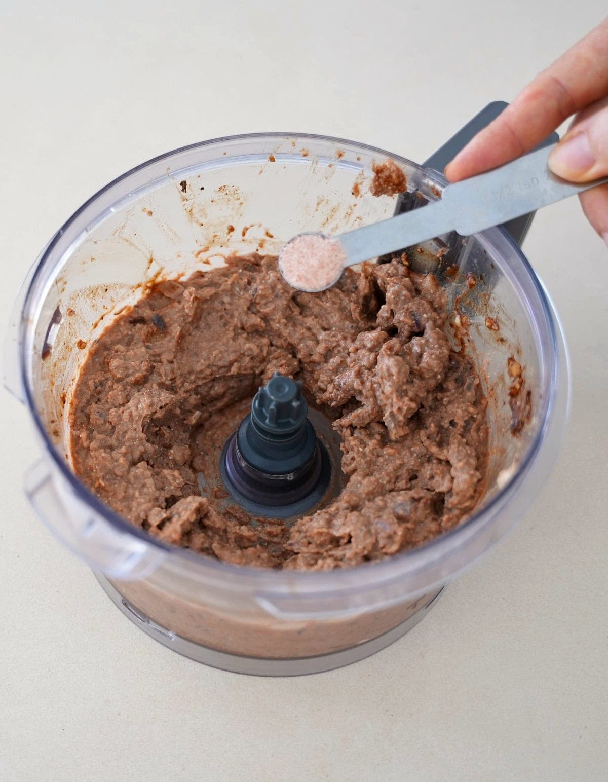 Adding salt to food processor containing vegan pate spread.