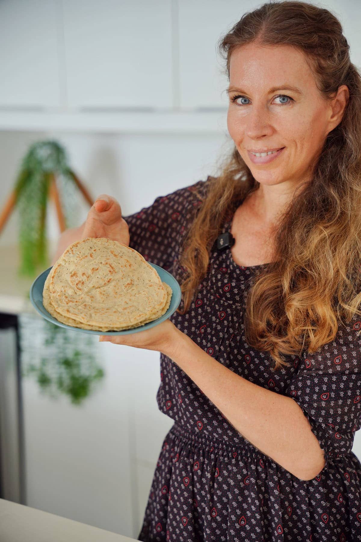 Michaela Vais smiling and holding a plate with oat chia wraps