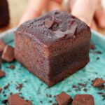 Hand holding small plate with a fudgy brownie