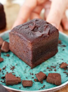 Hand holding small plate with a fudgy brownie