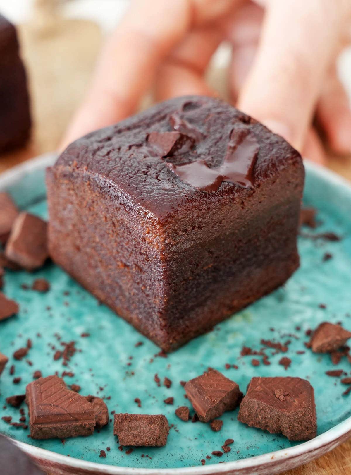 Hand holding small plate with a fudgy brownie