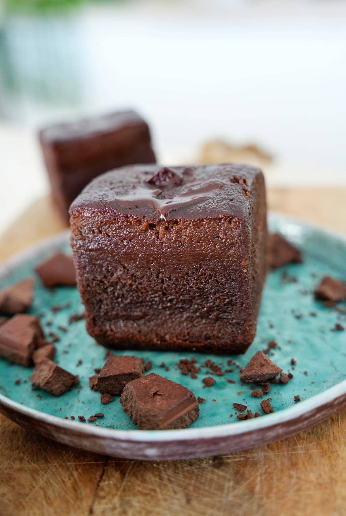 Red lentil brownie on small plate with some pieces of chocolate