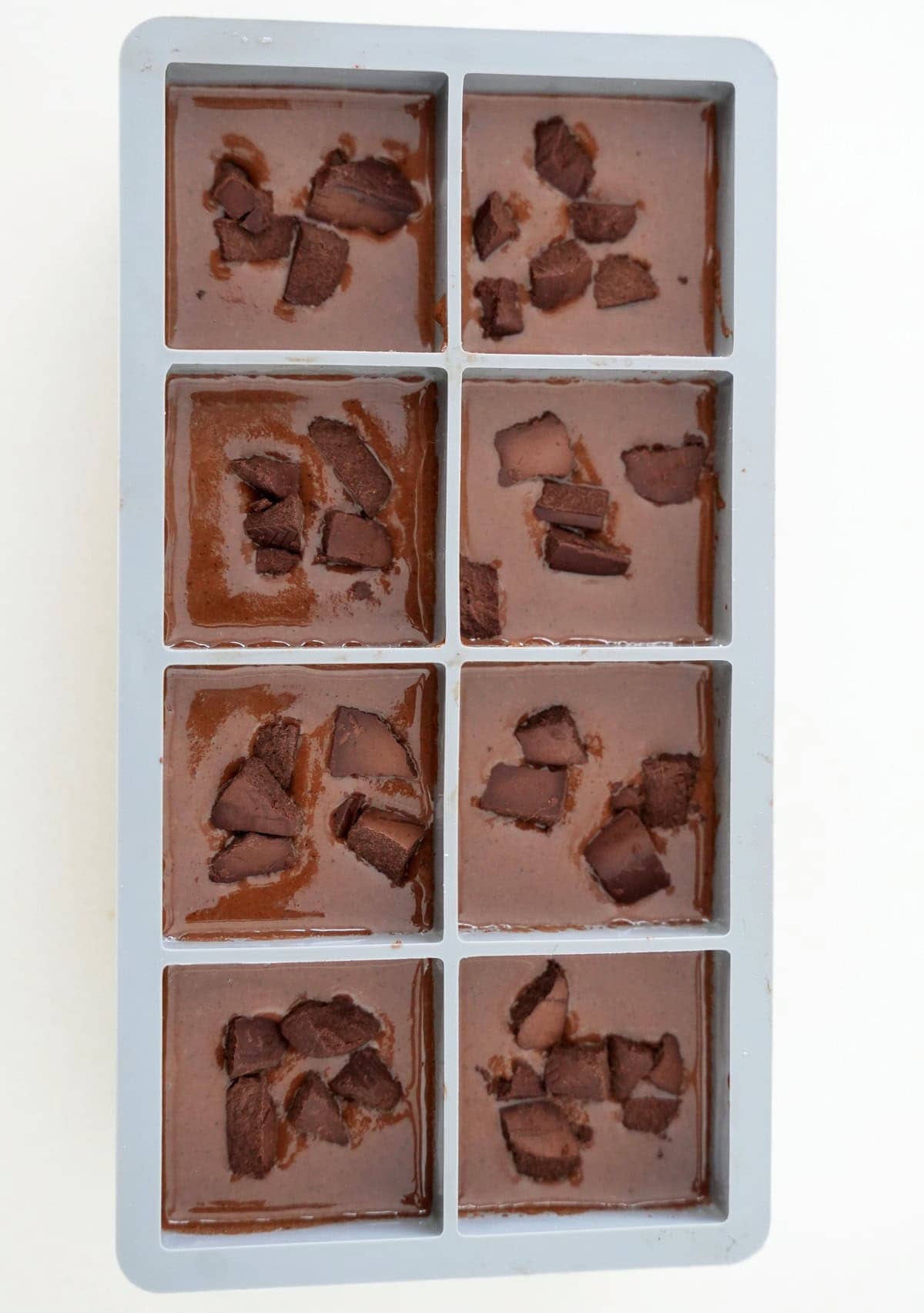 brownie batter in brownie silicone mold with chocolate before baking
