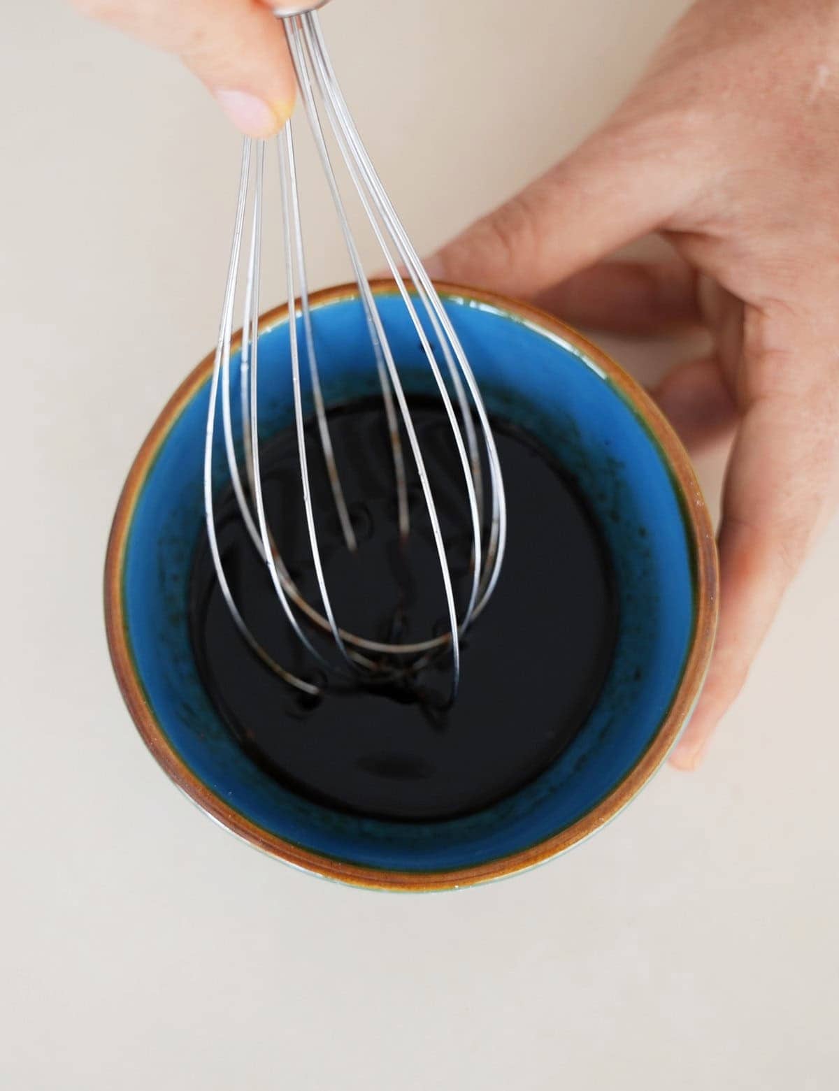Whisking vegan steak marinade in a small blue bowl.