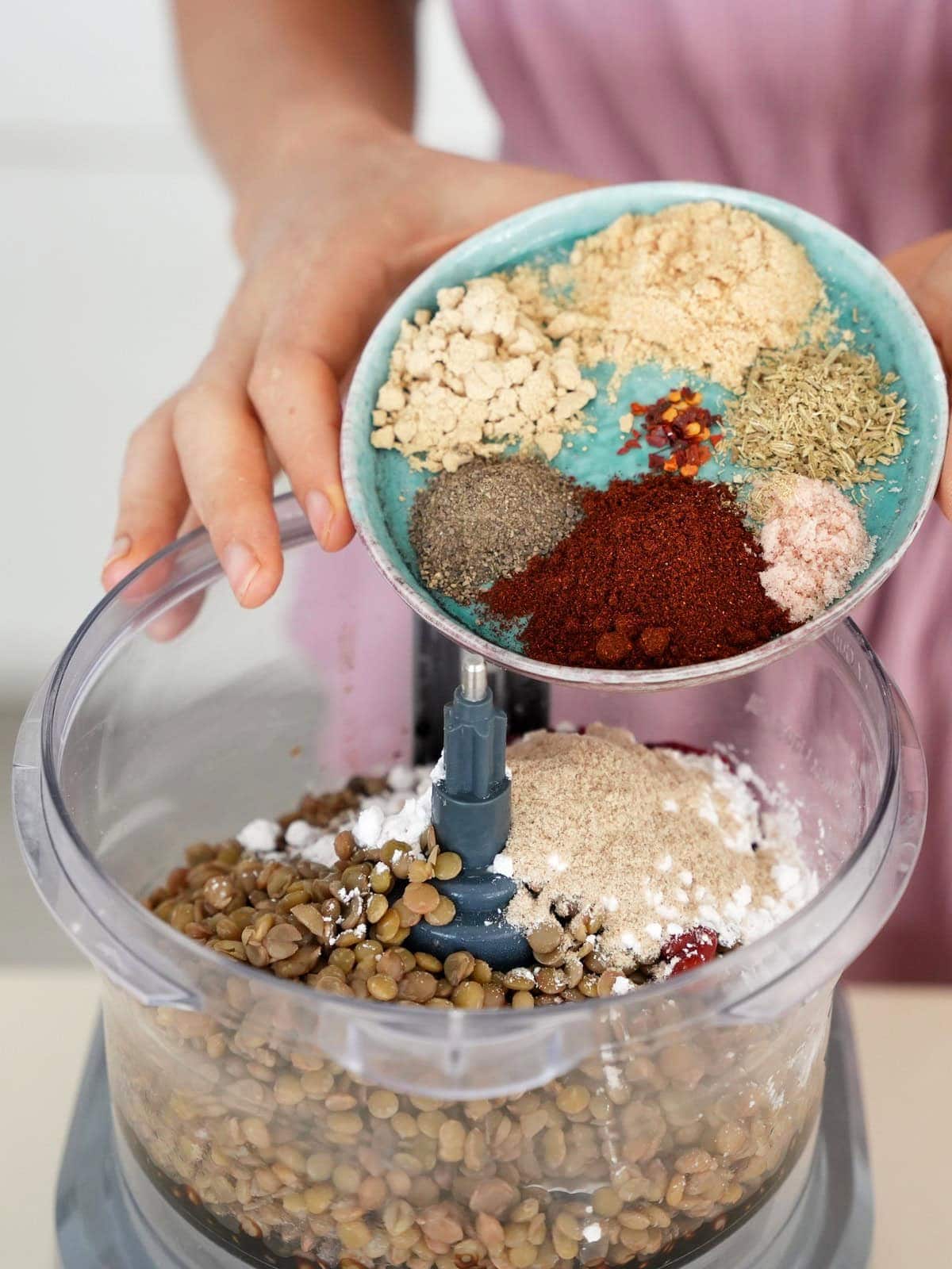 adding spices to food processor which contains lentils and flour